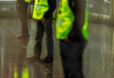 Security employees standing in a line at a stadium on a sporting event at night